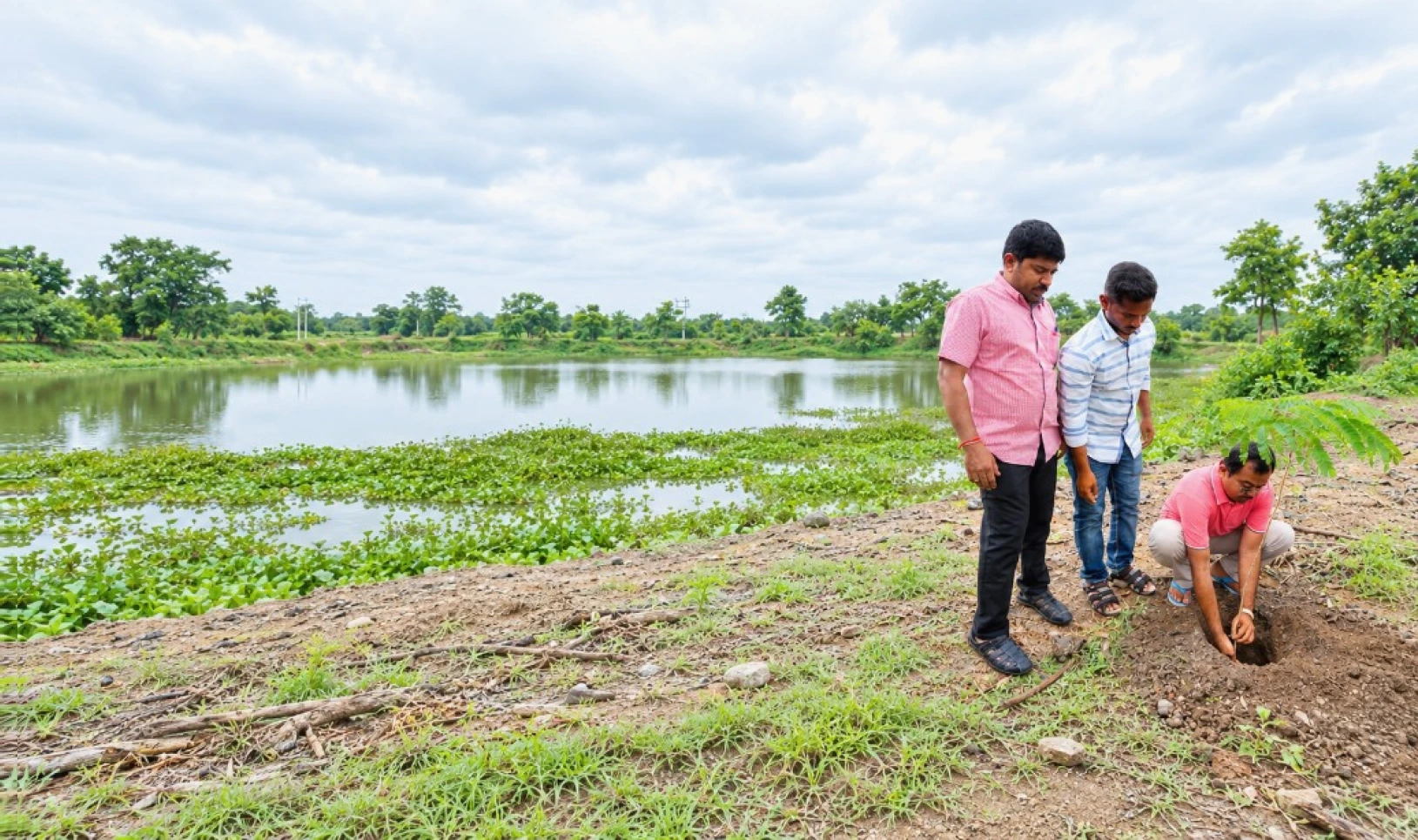 Team planting a sapling by a lakeside — environmental stewardship
